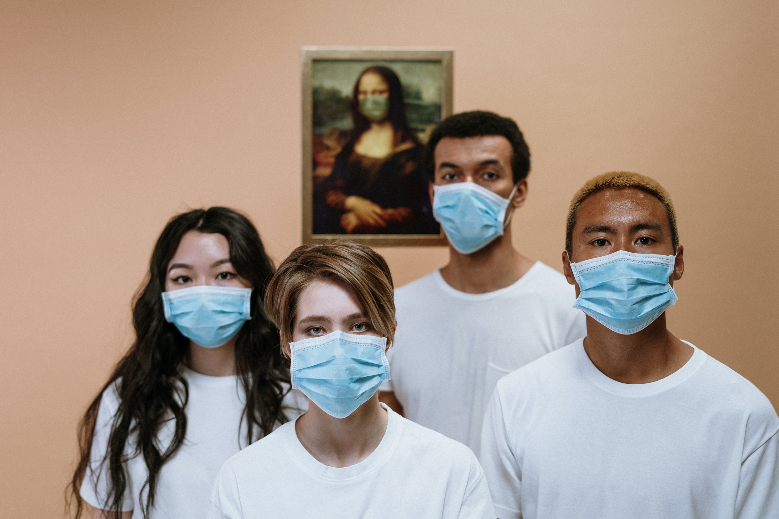 Een foto met vier mensen met een mondkapje voor.