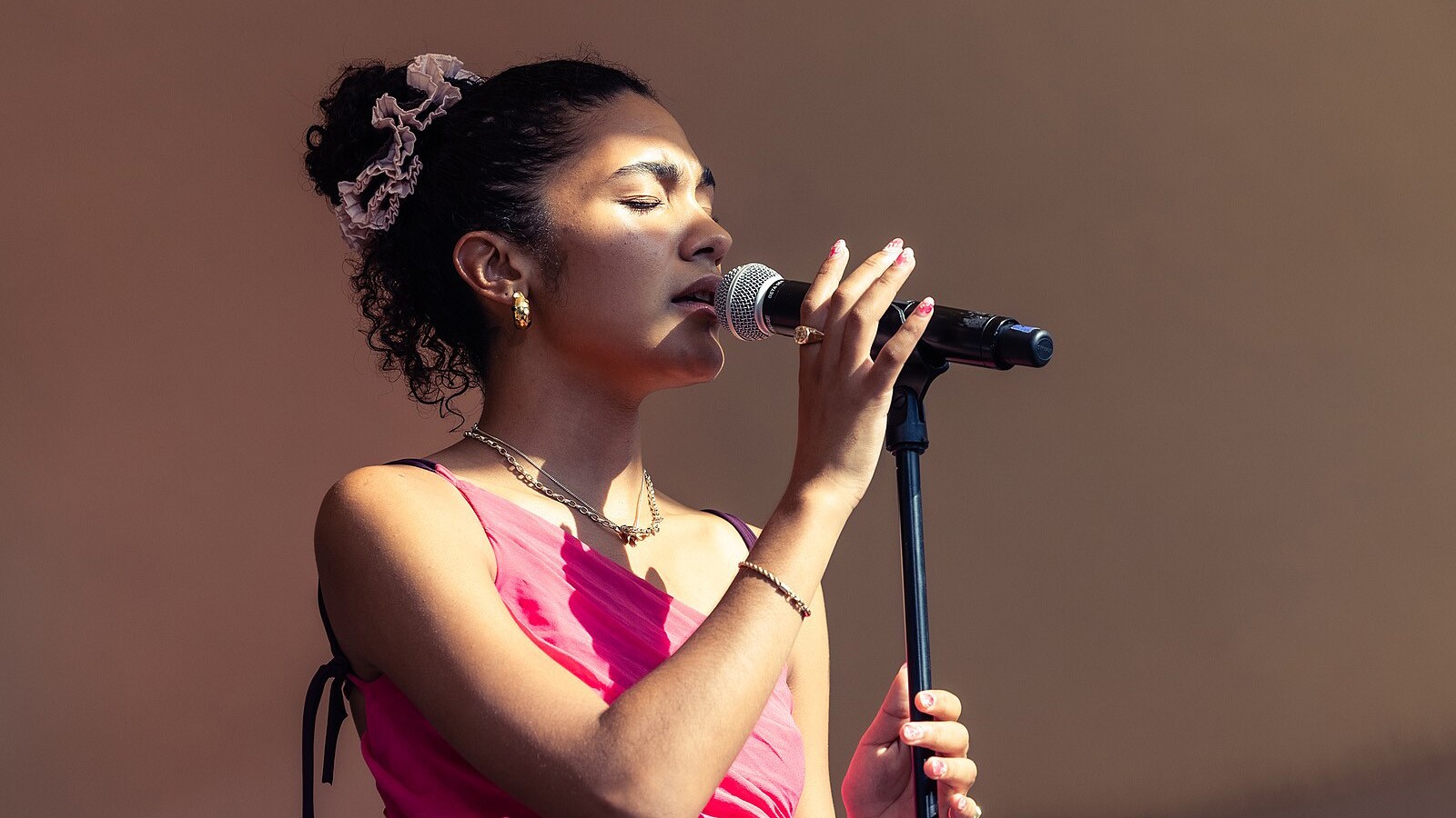 Olivia Dean zingt rustig op het podium tijdens een intieme live-show, terwijl ze pleit voor eerlijke en betaalbare concertkaartjes.