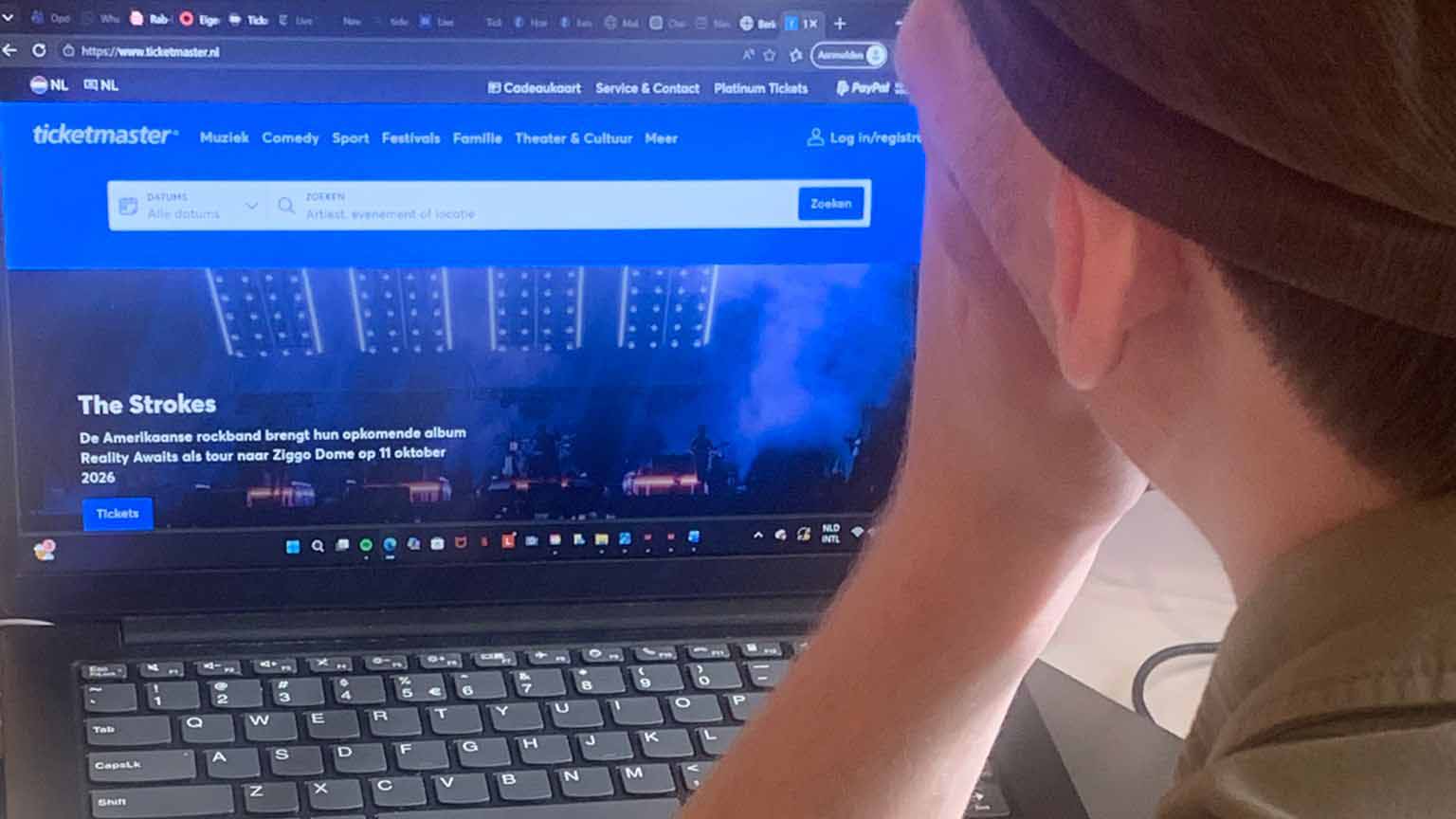 een jongen die naar de website van ticketmaster kijkt